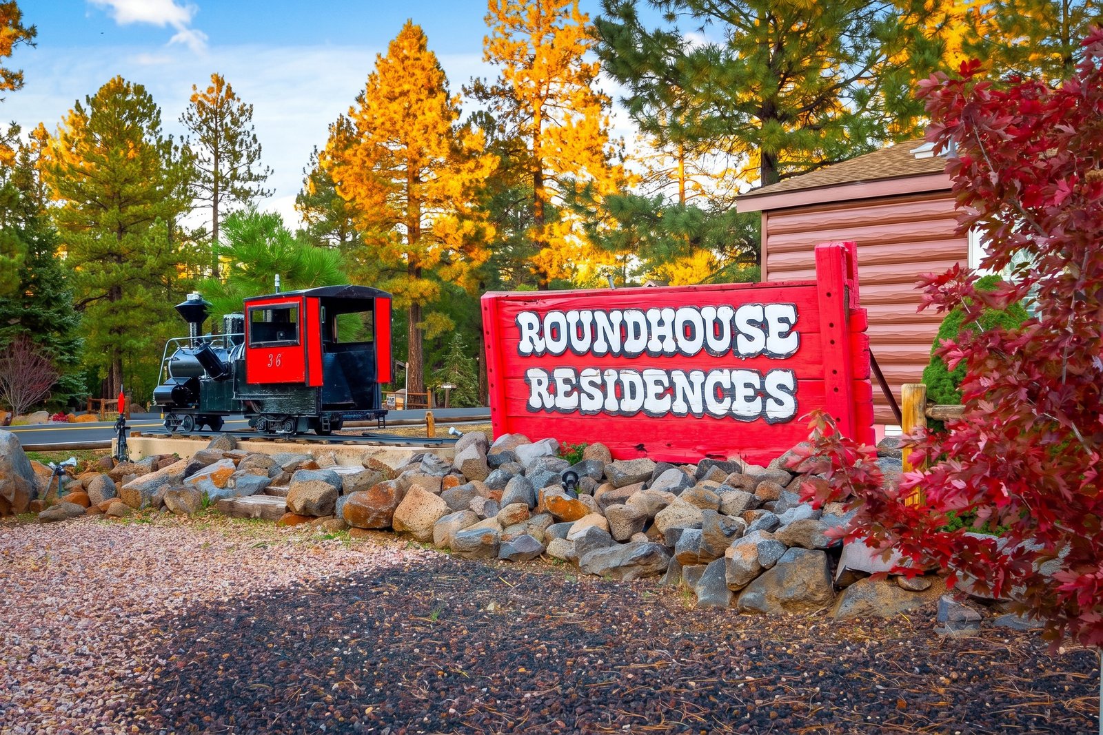 Roundhouse Residences sign with miniature train and fall foliage